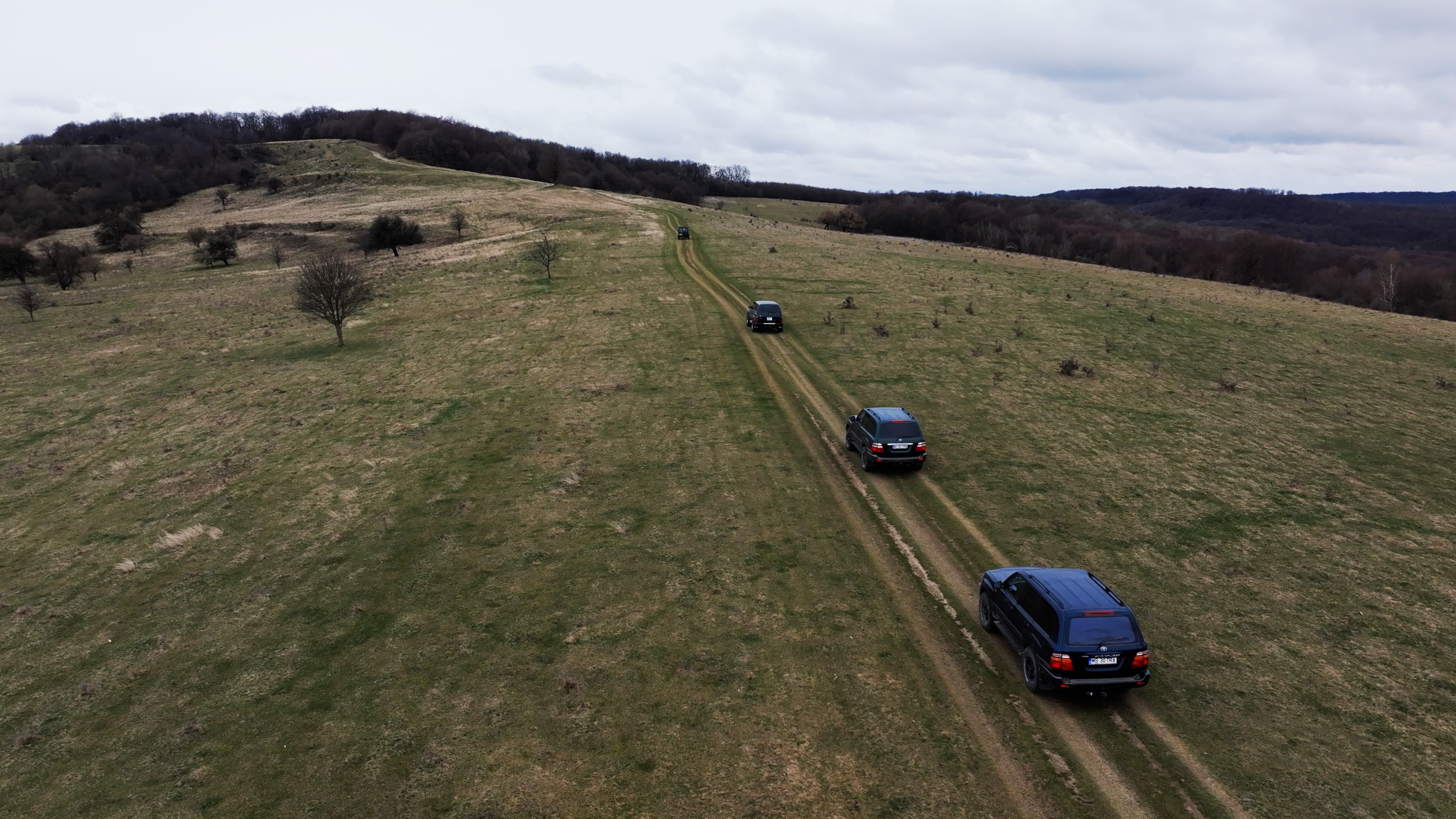 Convoy of 4x4 vehicles crossing open hills